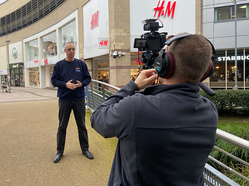 Camera operator films a piece to camera o a hertfordshire highstreet